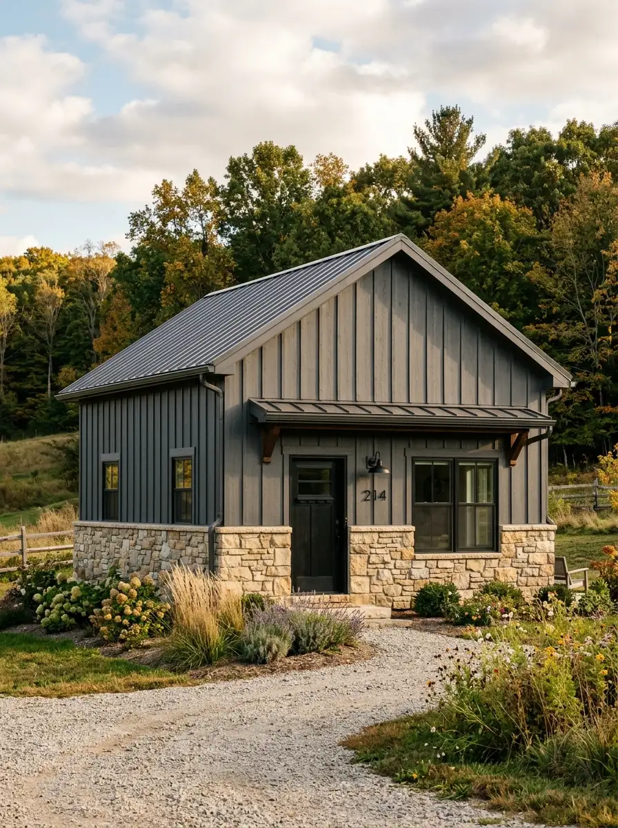 19 Stunning Small Barndominium Exterior Ideas That Prove Simple Barn House Designs Can Make a Big Impact 12 Small barndominium exterior with rough-cut limestone stone veneer foundation accent, dark gray board siding, black front door, and mature trees in background